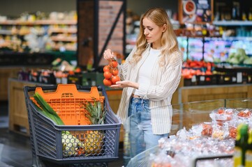 Girl choosing tomatoes in a food store or a supermarket