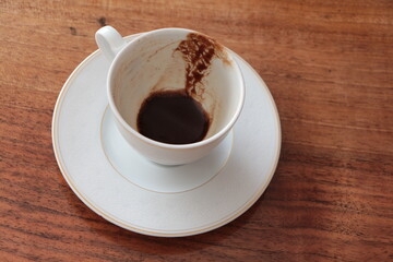 Cup of Turkish Coffee finish drinking, empty dirty cup. A cup of drunk coffee. Concept for completing a meeting or coffee break. Finished cup on the wooden table. Coffee grounds.