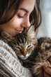 © Sam - A young woman with long brown hair gently cradles a tabby cat in her arms.