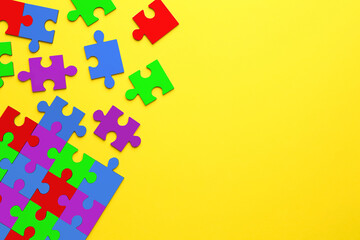 Wall Mural - Many colorful puzzle pieces on yellow background, top view. Symbol of autism