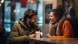 © NOPPHINAN - A cheerful couple dressed in warm clothing sharing a joyful moment while enjoying coffee at a cozy cafe, laughing and smiling, creating a warm and friendly atmosphere.