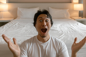 Wall Mural - Funny wow face asian man feeling amazing and present the bedroom of hotel.