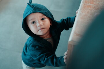 A cute child in a green hoodie exploring a vibrant indoor space with colorful furniture