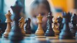 © NOPPHINAN - young child intently watches a chessboard, concentrating on the pieces in play, highlighting the strategy and focus in the game.