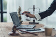 © Kritdanai - Lawyers at Work: A close-up shot of a lawyer's hand pointing at a laptop screen, with a gavel, scales of justice, and other legal paraphernalia in the background.