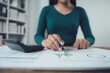 © Kritdanai - Analyzing the Data: A close-up shot of a businesswoman's hand meticulously analyzing a financial report, with a calculator and pen nearby.  The image embodies focus, precision.
