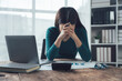 © Kritdanai - The Weight of Responsibility: A woman, surrounded by work documents, sits at her desk, her head in her hands, embodying the pressure and stress of modern work life.