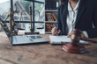 © Kritdanai - Legal Professional at Work:  A lawyer meticulously reviews documents at her desk, surrounded by legal symbols and technology, signifying diligence and expertise.