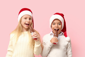 Cute little children eating chocolate Santa Claus on pink background