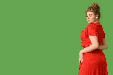 Wall Mural - Beautiful young woman in stylish red dress on green background