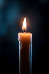 A single burning candle with wax dripping down the side against a dark blue background.