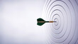 © ontsunan - Bullseye Precision, Green dart perfectly hits center of a white target, symbolizing accuracy and success
