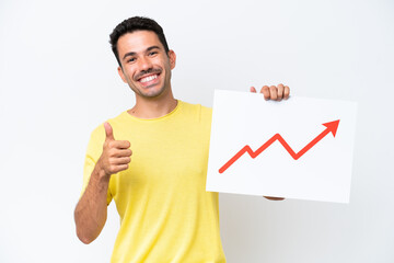 Young handsome man over isolated white background holding a sign with a growing statistics arrow symbol with thumb up