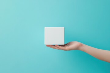 Hand holding blank white cube on blue background