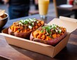 © Sergey - Two orange baked potatoes with a side of food in a cardboard box