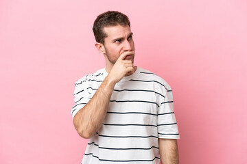 Wall Mural - Young caucasian man isolated on pink background having doubts and with confuse face expression