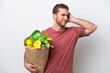 © luismolinero - Young caucasian man holding a grocery shopping bag isolated on white background having doubts