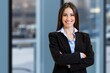 © Minerva Studio - Businesswoman smiling with arms crossed in office building
