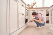 © elenavolf - Young woman checking oven in a modern kitchen setting for home cooking and interior design inspiration.