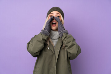 Wall Mural - Teenager blonde girl with winter hat over isolated purple background shouting and announcing something