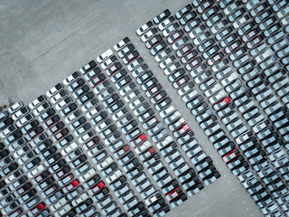 Aerial view of new cars stock at a large factory parking lot. Automotive industry, logistics operations, and vehicle storage for import and export. Key role in the global car market supply chain.