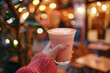 © Syuzann q - Hand holding a guava latte in a cozy cafe atmosphere