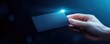 © Newvie - Hand holding a blank business card with a glowing edge, dark background