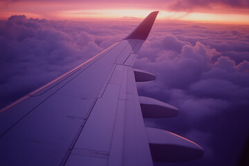 A view of the wing from inside an airplane window, with the sky painted in hues of blue and purple as it blends into orange at sunset. The sun is setting behind clouds