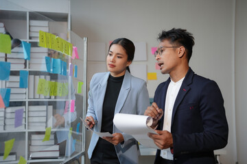 Wall Mural - business colleagues discussing new project ideas while using sticky notes on glass wall in modern of