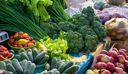 Fresh broccoli, cucumbers, apples, lettuce, tomatoes and green onions for sale at a farmers market in Provence, France. Vegetables are sold in mediterranean farmers fair. Healthy local food market. 