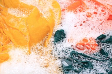 Sticker - Colorful clothes in suds, closeup. Hand washing laundry