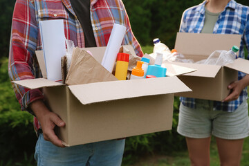 Sticker - Recycling. People holding cardboard boxes with different garbage outdoors, closeup