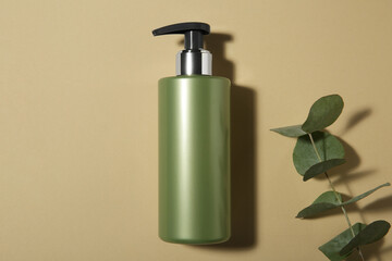 Poster - Bottle of shampoo and eucalyptus branch on beige background, flat lay