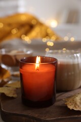 Canvas Print - Burning candle, cocoa and dry leaves on table, closeup. Autumn atmosphere