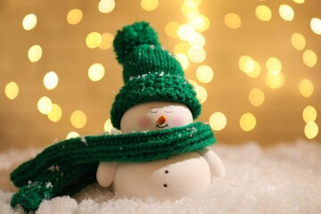 Canvas Print - Cute decorative snowman on artificial snow against blurred lights, closeup