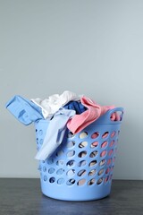 Sticker - Plastic basket full of laundry on table against grey background