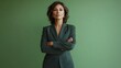 © Jittapon - Portrait of a determined and authoritative Hispanic middle aged woman wearing a sleek business pantsuit standing with a confident and poised demeanor against a plain sage green background