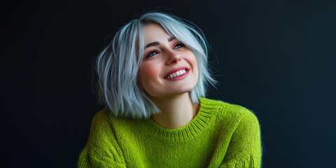 A woman with a modern haircut and stylish gray hair wears a vibrant green sweater and smiles subtly, embodying a youthful look and trendy fashion statement.