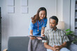© amnaj - Young female nurse is showing medical test results on a clipboard to a senior male patient while visiting him at home