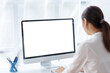 © amnaj - Businesswoman is sitting at her desk working on a computer with a blank white screen