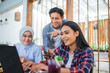 © Odua Images - three young people use a laptop together during group work with friends at a cafe