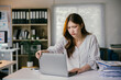 © PaeGAG - Asian businesswoman is closing her laptop in frustration while working at her desk in the office. She is surrounded by paperwork and appears to be overwhelmed