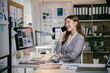 © PaeGAG - Businesswoman is working at her desk in a modern office, surrounded by paperwork and charts, smiling while talking on the phone