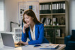 © PaeGAG - Young professional woman works happily at a modern office desk, surrounded by paperwork and technology, showcasing her corporate and entrepreneurial skills