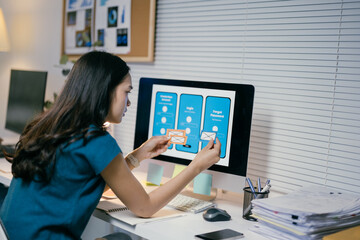 Young asian female designer is working on a mobile application prototype, arranging wireframes on her desktop computer screen