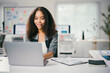 © PaeGAG - Cheerful young african american businesswoman works on a laptop in a bright office, exuding confidence and professionalism
