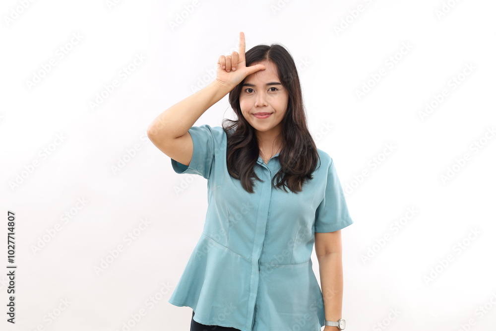 Smiling Asian girl makes loser gesture over forehead, lost shape L ...
