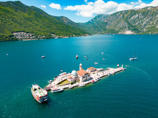 Aerial drone view of Sveti Dorde Island - Saint George Monastry in the middle of the island. In background is Perast city. Famous travel destination in Montenegro. Boats passing