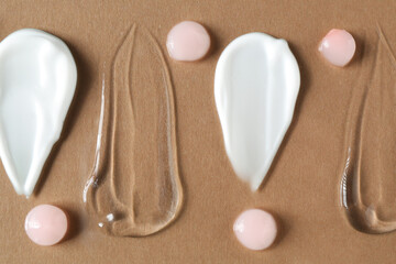 Poster - Smears of different cosmetic products on brown background, flat lay