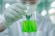 © ChaoticDesignStudio - A scientist examines a green liquid in a lab at a research facility during a regular experiment